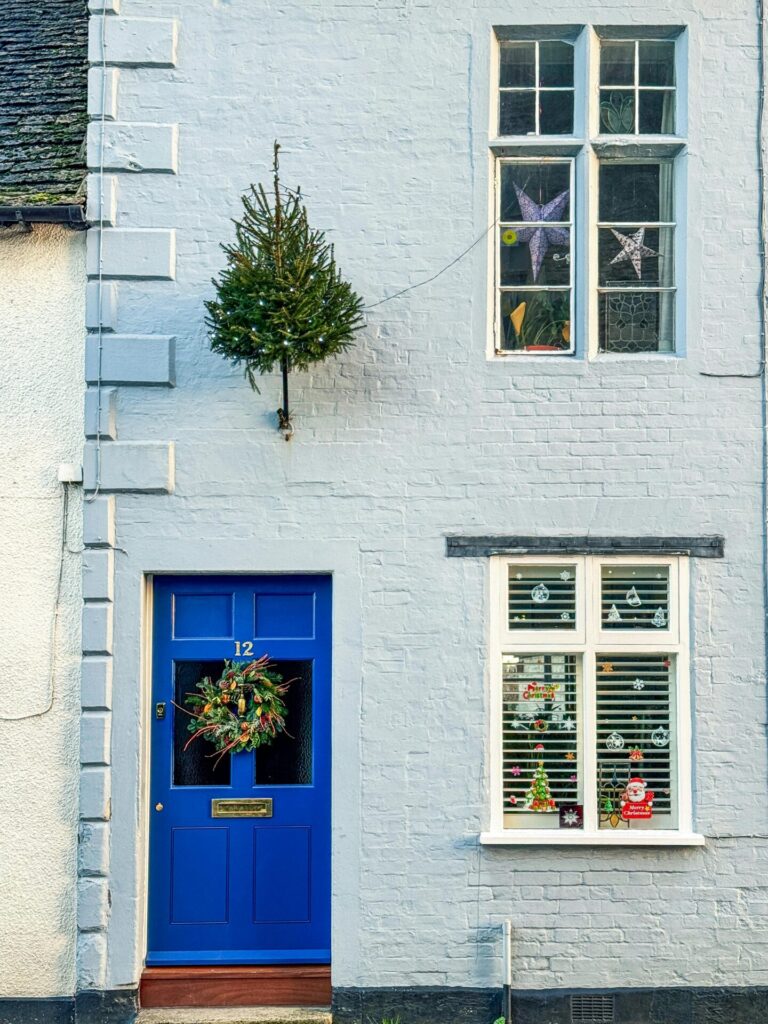 House front with blue door, windows and various Christmas decorations